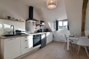 eine Küche mit weißen Schränken, einem Herd und einem Tisch in der Unterkunft Les Trois Rois 5 - Centre Avranches in Avranches