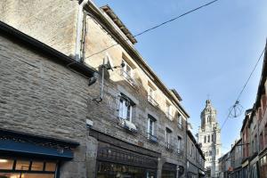ein altes Backsteingebäude mit einem Uhrturm im Hintergrund in der Unterkunft Les Trois Rois 5 - Centre Avranches in Avranches