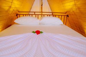 a white bed with a red flower on it at Villa Anaa in Habaraduwa Central