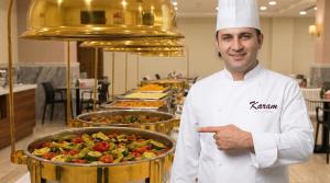 uno chef in piedi di fronte a un buffet di cibi di فندق كرم مضياف Karam Medyaf Hotel a Al Khansāk