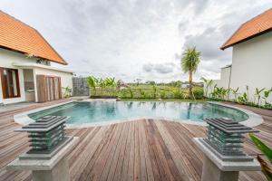 a swimming pool with a wooden deck and a house at Svadarma Bali Villa in Darmasaba