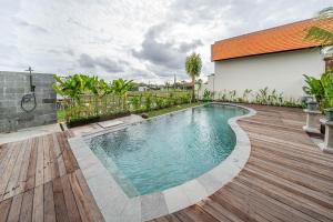 a swimming pool in a backyard with a wooden deck at Svadarma Bali Villa in Darmasaba