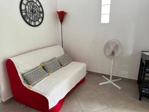 een kamer met een bank, een ventilator en een klok bij Ti Kaz Lol in Saint-Paul