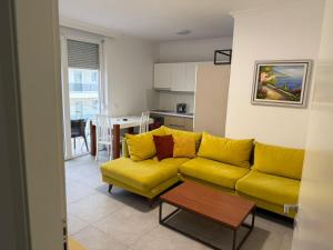 a living room with a yellow couch and a kitchen at Holiday home Shengjin k in Shëngjin