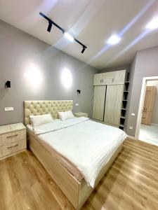 una camera da letto con un letto grande con lenzuola bianche di Eco Apartments a Yakkasaray