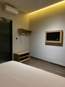 een slaapkamer met een bed en een tv aan de muur bij Moonstone in Bandung