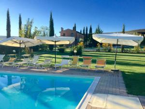 a swimming pool with chairs and umbrellas next to at Agriturismo Marinello in Pienza