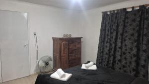 a bedroom with a bed and a dresser and a fan at Complejo Casablanca Plottier in Plottier