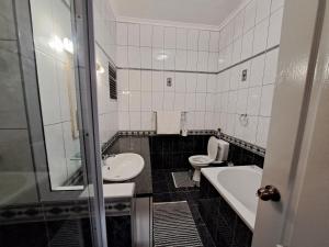 a bathroom with a toilet and a tub and a sink at Das Moven Haus in Swakopmund +25 photos