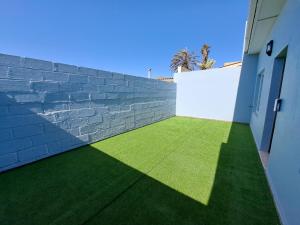 a brick wall with green grass next to a building at Das Moven Haus in Swakopmund