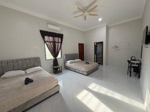 a bedroom with two beds and a ceiling fan at Sasuka Inn Rusila in Marang +16 photos