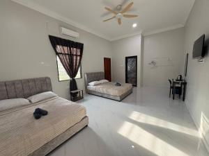 a bedroom with two beds and a ceiling fan at Sasuka Inn Rusila in Marang