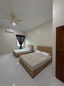 a bedroom with two beds and a ceiling fan at Sasuka Inn Rusila in Marang