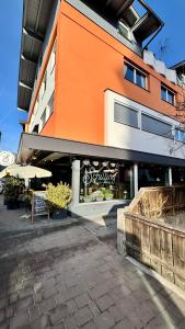 un edificio arancione e bianco con tavoli e ombrelloni di SCHILLING stay&more a Wörgl