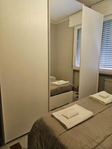 een slaapkamer met een spiegel en een bed met handdoeken erop bij Appartamento vicino lo stadio con garage in Piacenza