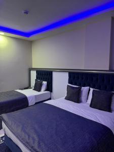 two beds in a hotel room with blue lights at Ögel Apart Otel in Sarıkamıs