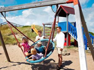 een gezin dat op een schommel zit op een speelplaats bij 8 person holiday home in Ringkøbing-By Traum in Ringkøbing