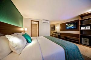 a bedroom with a large white bed and a desk at Flat Radisson Hotel Belem in Belém