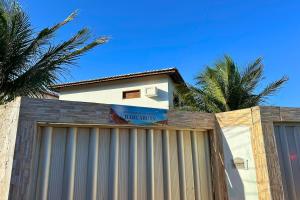 a building behind a fence with palm trees in the background at Maré · Casa Maré in Aracati +32 photos