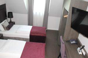 a hotel room with two beds and a flat screen tv at Fair Hotel Europaallee in Frankfurt