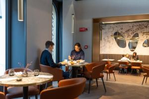 two people sitting at tables in a restaurant at Palazzo 4 Fontane 12 in Rome