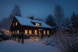 a house with lights on in the snow at night at Chata Koza in Bublava