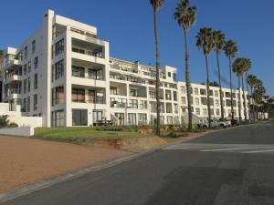 a large white building with palm trees in front of it at Point Village Accommodation - Santos 5 in Mossel Bay