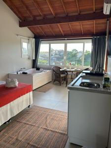a bedroom with a bed and a bathroom with a tub at Pousada Vielas do Rosa - centrinho da praia do rosa in Praia do Rosa