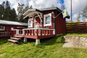 una piccola casa rossa con un portico e una bandiera di BLE936-Braekne-Hoby-Jaernaviksvaegen-18 a Bräkne-Hoby