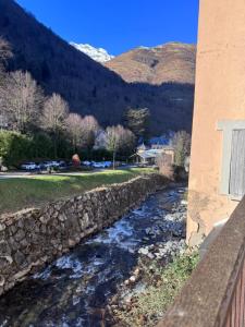 Een rivier naast een stenen muur met bergen op de achtergrond. bij Résidence Le Georgina in Cauterets