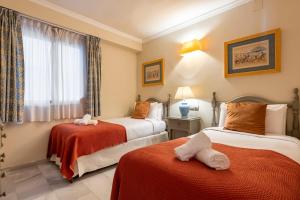 a hotel room with two beds and a window at RgHost-Apartamento España en Paseo Marítimo in Málaga