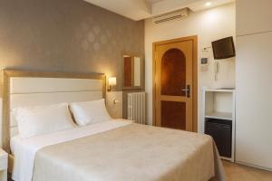 a bedroom with a white bed and a television at ELISABETTA hotel in Cesenatico +21 photos