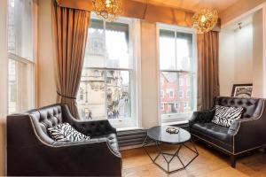 een woonkamer met twee stoelen en een tafel en ramen bij Museum Residence Oxford in Oxford