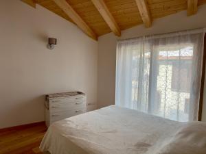 a bedroom with a bed and a window with a dresser at Chalet Ski Home - Madesimo in Madesimo