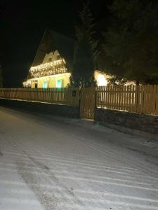 een huis met kerstverlichting aan een hek 's nachts bij Dom na Wynajem - Bartoszówka in Ochotnica Górna