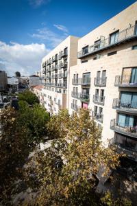 an apartment building with a tree in front of it at Jrose Hotel in Jerusalem
