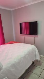 una camera da letto con un letto e una televisione a parete di Riley's Place a Cape Town