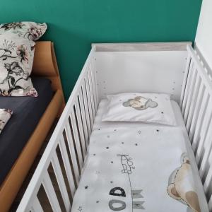 un berceau blanc avec un lit et un lit bébé dans l'établissement Ferienwohnung Wiesengrund, Ruhig im Ortsteil von Roth, nähe Rothsee, 25 min Messe Nbg, à Roth