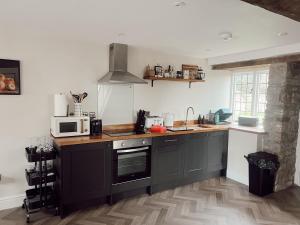 a kitchen with black cabinets and a microwave at Gardener's Cottage at Mathern Palace in Chepstow