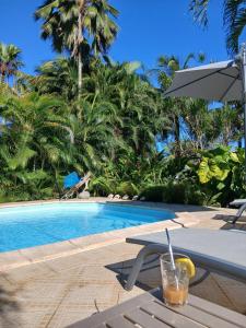 a drink on a table next to a swimming pool at La Kaz Kako in Sainte-Rose