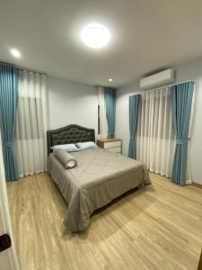 a bedroom with a large bed with blue curtains at Alayah บ้านเดี่ยวสองชั้น ธาดาดิโอเอซิส in Ban Krok Khi Nu +33 photos