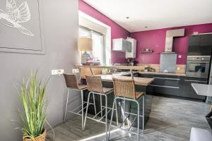 a kitchen with purple walls and a bar with stools at Le Vincennes, simple et atypique ! in Cholet