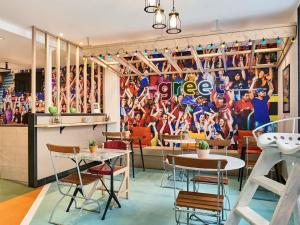 een restaurant met tafels en stoelen en een muur met een voetbalmuurschildering bij Greet Boulogne Billancourt Paris in Boulogne-Billancourt