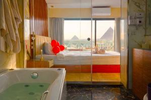 un bagno con vasca e un letto con finestra di Zoom Pyramids View inn a Il Cairo