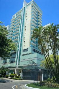 a tall building with a palm tree in front of it at Flat Praia do Canto 2Q-2B Long Stay TRIÂNGULO DAS BERMUDAS in Vitória