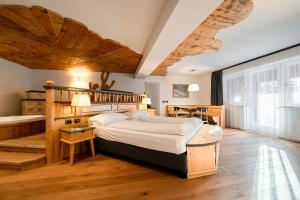 a bedroom with a large bed and a wooden ceiling at Croce Bianca Leisure & Spa Hotel in Canazei +140 photos
