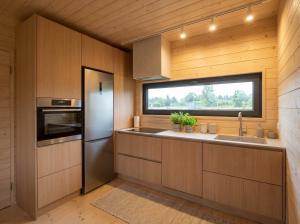 eine Küche mit einem Kühlschrank und einem Fenster in der Unterkunft Domki Lubikowo in Lubikowo