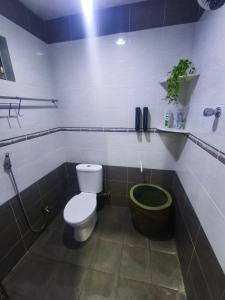 ein Badezimmer mit Toilette und grünem Eimer in der Unterkunft Dreamy Stay Penang in Butterworth