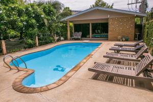 a swimming pool with lounge chairs next to a house at United Place in Bangsaen