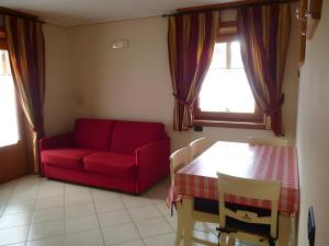 un soggiorno con un divano rosso e un tavolo di Martin Haus a Livigno Altre 11 foto